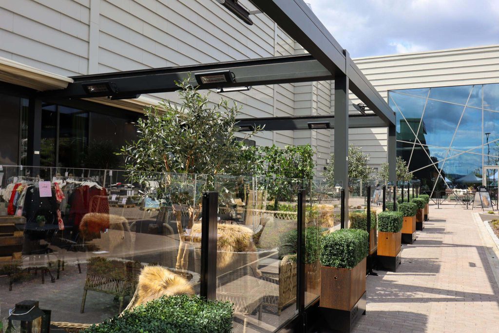 Uteservering med pergola, varmelamper og glassgjerder