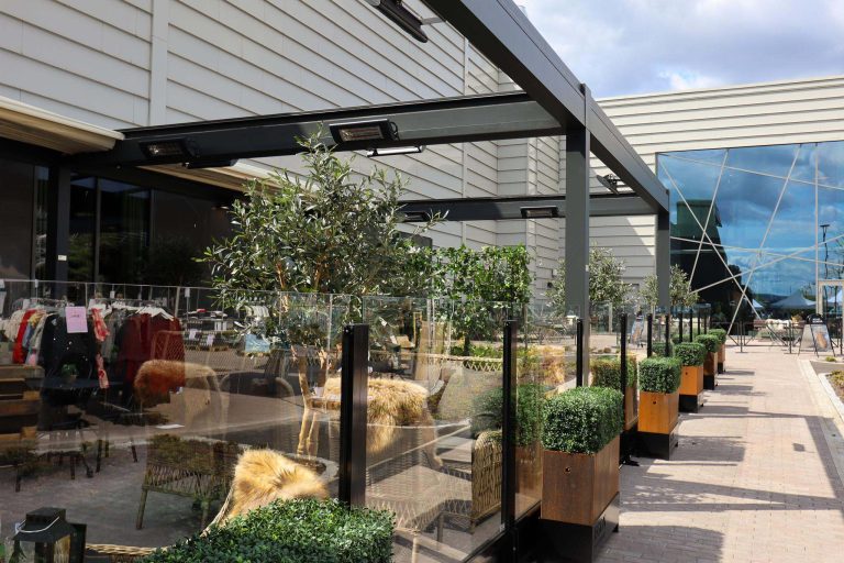 Uteservering med pergola, varmelamper og glassgjerder